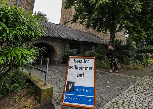 Ein Willkommenschild steht auf einem gepflasterten Vorplatz einer Kirche