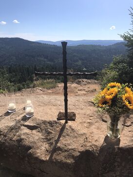 Eisenkreuz, Kerzen und Sonnenblumen auf einem Steinaltar auf dem Silberberg.