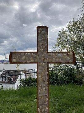 Ein mit Muscheln besetztes Kreuz vor der Elbe.
