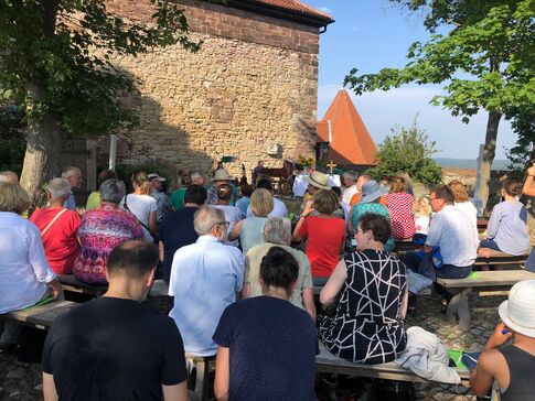 Viele sitzende Menschen von hinten auf Bänken im Innenhof der Leuchtenburg.