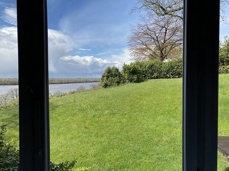 Blick aus dem Fenster auf einen Garten und die Elbe bei Hamburg