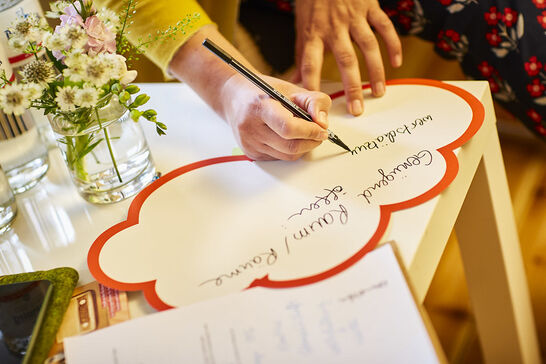 Eine Hand schreibt auf eine Wolke aus Papier