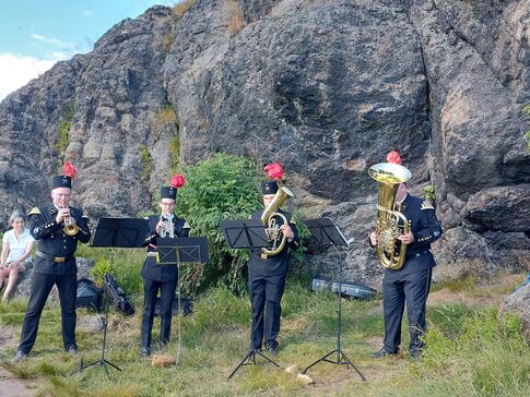 Vier Männer in Uniform mit Blechblasinstrumenten auf einem Berg.