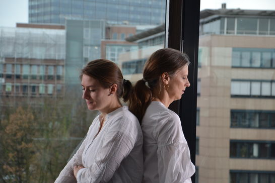 Linda Giering und Sabine Henning stehen Rücken an Rücken vor einem Fenster.