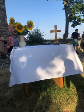 Ein Altar mit Kreuz und Sonnenblumen im Freien.