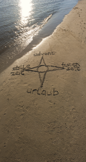 Eine in den Sand gezeichnete Kompassrose am Meeressaum