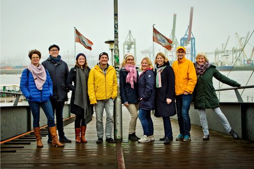 Die redaktion des Anderen Advent an einem grauen Wintertag auf dem Anleger zum Museumshafen Neumühlen an der Elbe.